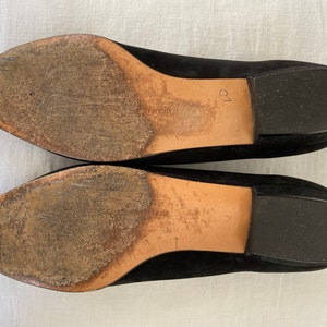K&ouml;nnte beinhalten: Ein Paar schwarze Wildlederschuhe mit Ledersohlen. Die Sohlen sind abgenutzt und weisen Gebrauchsspuren auf. Die Schuhe sind Gr&ouml;&szlig;e 39.