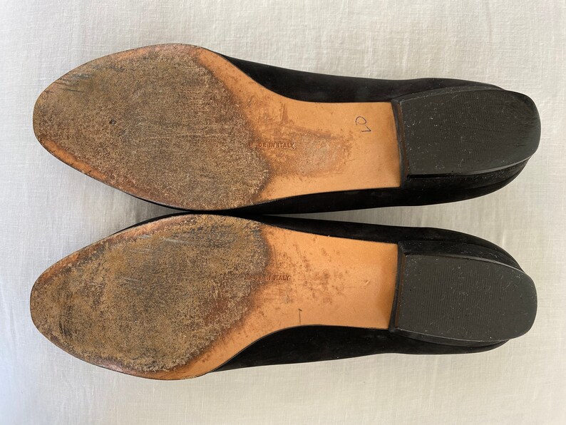 K&ouml;nnte beinhalten: Ein Paar schwarze Wildlederschuhe mit Ledersohlen. Die Sohlen sind abgenutzt und weisen Gebrauchsspuren auf. Die Schuhe sind Gr&ouml;&szlig;e 39.