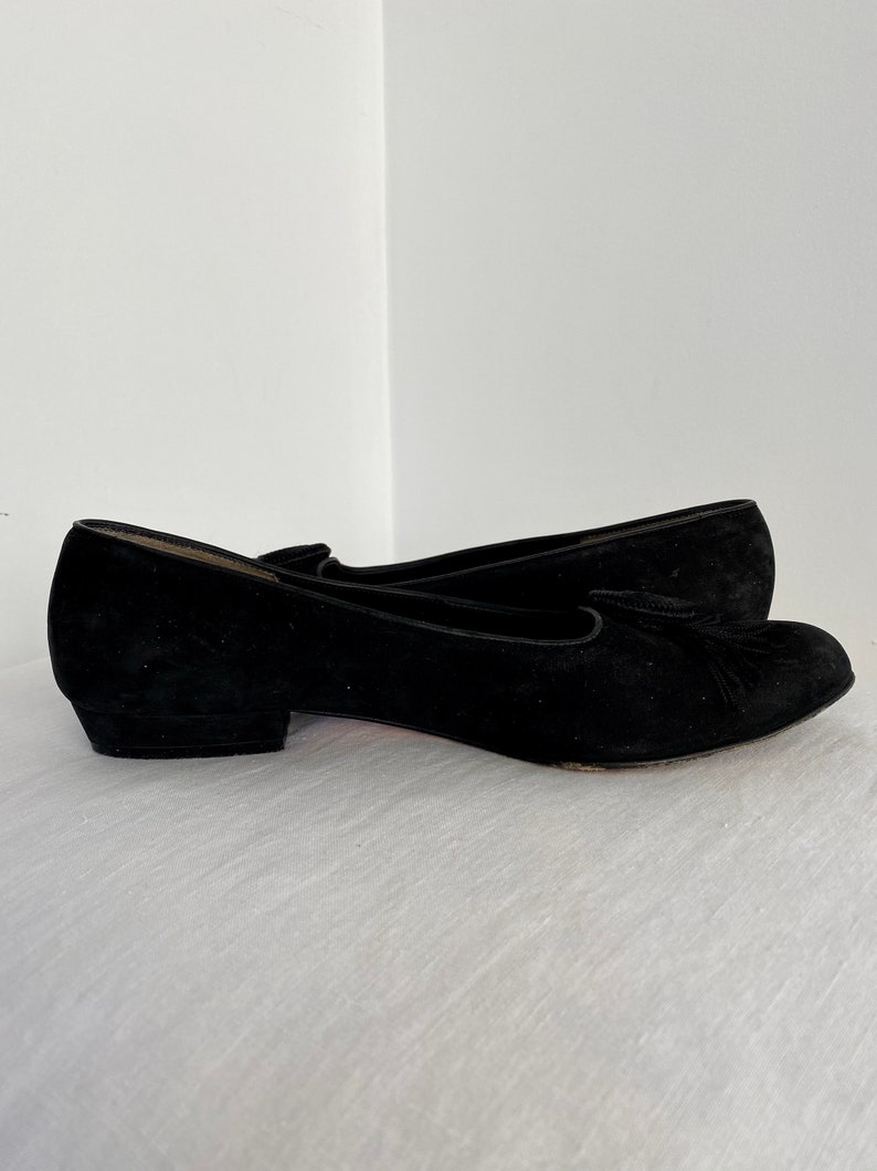 K&ouml;nnte beinhalten: Ein Paar schwarze Wildlederschuhe mit Absatz und einem Quasten-Detail an der Spitze.