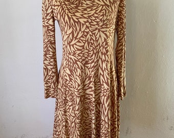 May include: A long-sleeved dress with a brown and cream abstract leaf pattern. The dress has a round neckline and a flowing skirt.