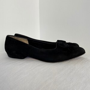 K&ouml;nnte beinhalten: Schwarze Ballerinas aus Wildleder mit einem kleinen schwarzen Quasten-Detail an der Spitze.