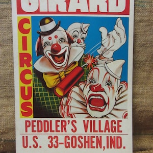 May include: Vintage circus poster featuring three clowns with exaggerated features. The poster has the text "GIRARD CIRCUS" in large letters, along with the location and dates of the event: "PEDDLER'S VILLAGE U.S. 33-GOSHEN, IND. JULY 6-7-8."
