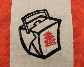 May include: A black and white illustration of a Chinese takeout container with a red Chinese character on the side. The container is drawn in a cartoon style and has a handle on top.