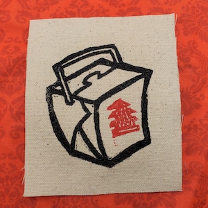 Pode incluir: Uma ilustração em preto e branco de um recipiente de comida chinesa para levar com um caractere chinês vermelho no lado. O recipiente é desenhado em estilo de desenho animado e tem uma alça na parte superior.