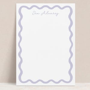 May include: A white notepad with a lavender scalloped border. The name "Jen Alvarez" is written in cursive at the top of the notepad.