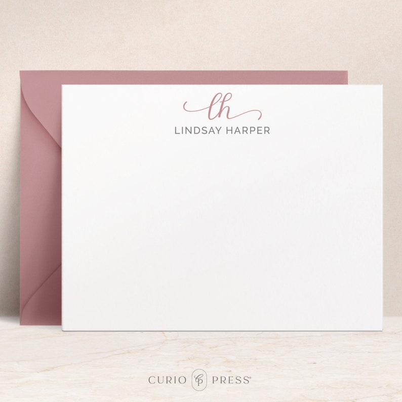 Op de afbeelding: Witte briefpapierkaart met een roze cursief monogram "lh" en de tekst "LINDSAY HARPER" eronder.