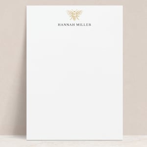 May include: White notepad with a gold bee illustration and the text "HANNAH MILLER" at the top.