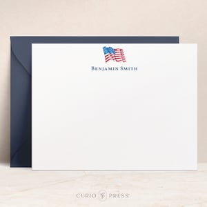 K&ouml;nnte beinhalten: Wei&szlig;e Briefpapier mit einer blauen und roten amerikanischen Flagge Grafik und dem Text "BENJAMIN SMITH" in blau.