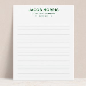 May include: White lined stationery with the text "JACOB MORRIS" in green, followed by "LETTERS FROM CAMP KENOSHA" and "SUMMER 2025" with an arrow. The paper is blank and ready for writing.