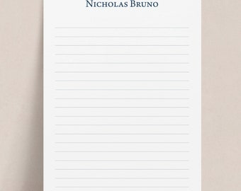 May include: A white lined notepad with the name "Nicholas Bruno" printed in dark blue at the top.