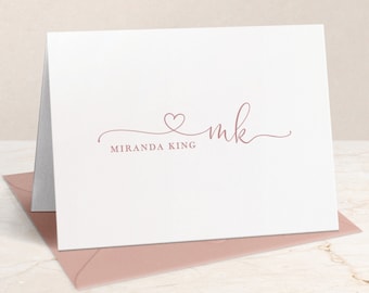 Könnte beinhalten: Gefaltete weiße Schreibwarenkarte mit einem mauvefarbenen Herz und den Initialen "mk" in zarter Schrift. Der Name "Miranda King" ist darunter gedruckt. Die Karte liegt auf einem passenden mauvefarbenen Umschlag.