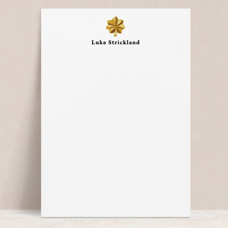 May include: White notepad with a gold star and the text "Luke Strickland" printed in black.