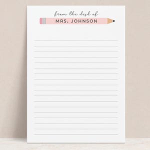 May include: A lined notepad with a pink pencil graphic at the top. The text "from the desk of MRS. JOHNSON" is printed above the lines. The pencil has a pink eraser and a black tip.