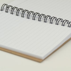 May include: A blank, lined notebook with a black wire-o binding. The notebook has a brown cardboard cover.
