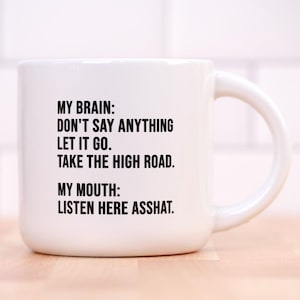 May include: White ceramic coffee mug with black text that reads "MY BRAIN: DON'T SAY ANYTHING LET IT GO. TAKE THE HIGH ROAD. MY MOUTH: LISTEN HERE ASSHAT."