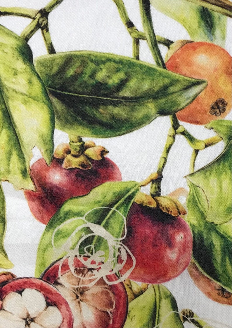 May include: A close-up of a white fabric with a watercolor illustration of mangosteen fruit and green leaves.