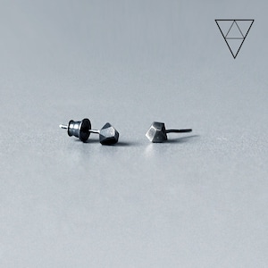 Op de afbeelding: Een paar zilveren geometrische oorbel studs. Elke oorbel heeft een facetgeslepen, hoekig ontwerp.