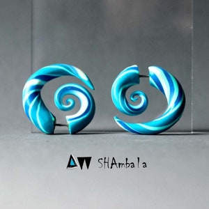 Könnte beinhalten: Ein Paar blaue und weiße spiralförmige Ohrringe. Die Ohrringe sind aus Polymer Clay gefertigt und haben eine glänzende Oberfläche.