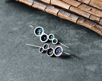 May include: A pair of silver earrings with a cluster of small, round, iridescent glass beads. The beads are set in silver and have a dark, almost black, color with hints of blue and green.