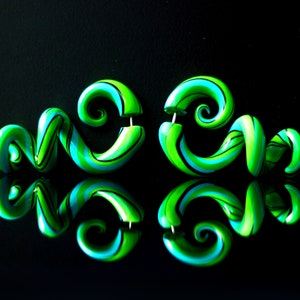 May include: A pair of green and blue spiral shaped earrings. The earrings are made of polymer clay and have a swirl pattern.