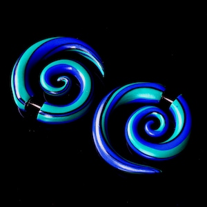 May include: A pair of blue and green spiral ear gauges. The gauges are made of wood and have a spiral design.