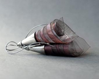 May include: A pair of earrings with a silver metal base and a pink and black fabric flower design.