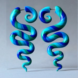 May include: A pair of blue, green, and purple spiral earrings. The earrings are made of polymer clay and have a unique, swirly design.