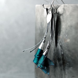 May include: Teal blue ribbon flower dangle earrings with silver wire and heart-shaped charms.