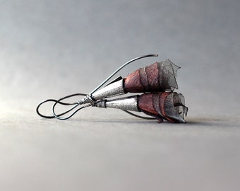 May include: A pair of silver wire earrings with brown and black fabric flowers.