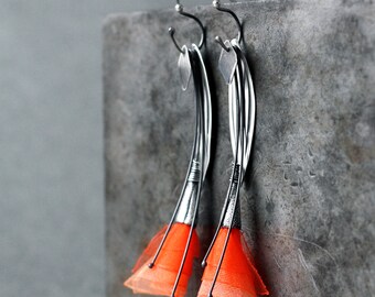 May include: A pair of silver earrings with orange fabric flowers. The earrings are made of thin, twisted wire and have a delicate, feminine design.