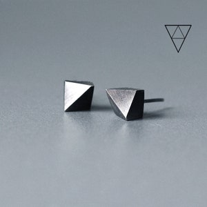 Può includere: Un paio di orecchini a bottone geometrici neri a forma triangolare.