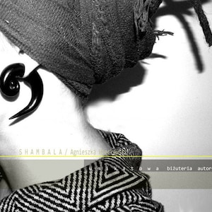 May include: A black and white image of a person wearing a black and white striped shirt with a large black spiral ear gauge. The text "SHAMBALA / Agnieszka G.  Gleskowska" is visible at the top of the image. The text "unikatowa biżuteria autorska" is visible at the bottom of the image.