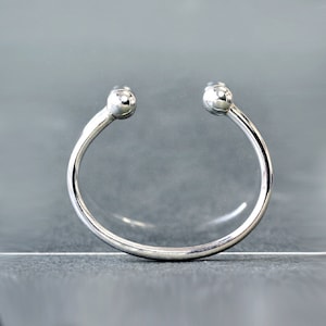 May include: A silver bangle bracelet with two round balls at the ends.