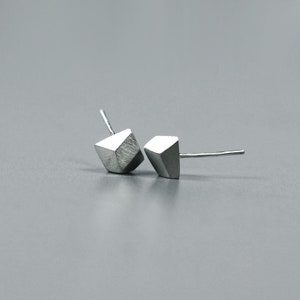 May include: A pair of silver geometric stud earrings. The earrings are shaped like a diamond and have a brushed finish.