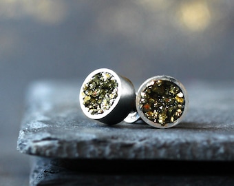 Op de afbeelding: Een paar zilveren oorbel studs met ronde groene en gouden pyriet stenen.