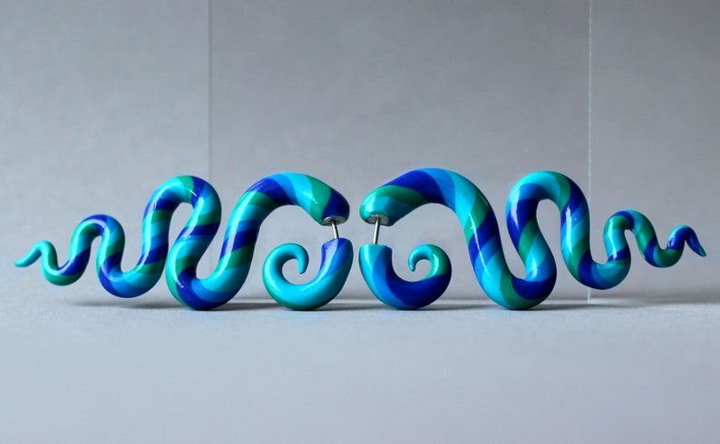 May include: A pair of blue, green, and purple spiral shaped earrings. The earrings are made of polymer clay and have a shiny finish.