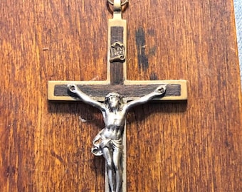 May include: A silver crucifix with a dark wood cross and a silver figure of Jesus Christ. The crucifix is hanging on a wooden wall.