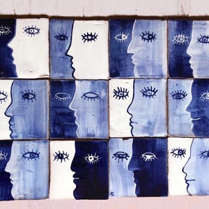 Könnte beinhalten: Eine Sammlung von Keramikfliesen, jede mit einem Profil eines Gesichts in Blau- und Weißtönen. Die Gesichter wechseln zwischen hellen und dunklen Hintergründen, mit einem Augendesign über jedem Profil. Die Fliesen sind in einem Raster angeordnet.