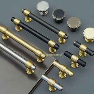 以下が含まれることがあります： キャビネット用の金具のコレクション。ハンドルとノブが含まれています。ハンドルは黒、金、銀の仕上げで、金のアクセントが付いています。ノブは丸く、さまざまな金属仕上げがあります。ハードウェアはグレーの表面に表示されています。