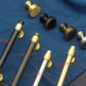 May include: A selection of cabinet hardware in various finishes, including black, antique bronze, brushed nickel, and brushed brass. The image shows both knobs and pulls, with gold accents. The text "Dreamchise" is visible.