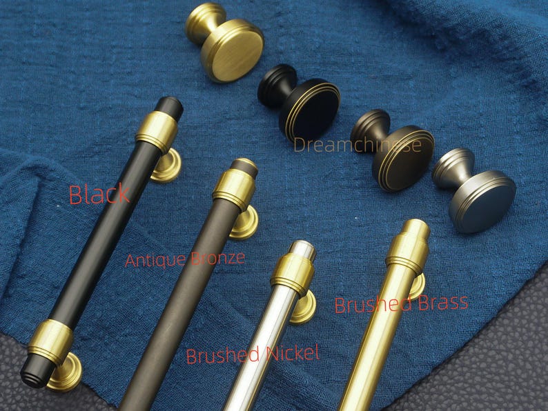 May include: A selection of cabinet hardware in various finishes, including black, antique bronze, brushed nickel, and brushed brass. The image shows both knobs and pulls, with gold accents. The text "Dreamchise" is visible.