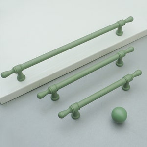 May include: Three green metal cabinet pulls with rounded ends and a single knob in the center. The pulls are of varying lengths. A single green knob is also shown.