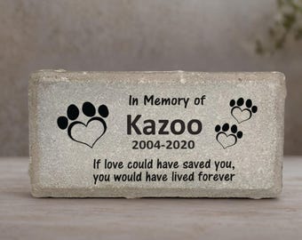 May include: A rectangular, light gray pet memorial stone. Black paw prints and hearts flank the text "In Memory of Kazoo 2004-2020." The inscription reads, "If love could have saved you, you would have lived forever."