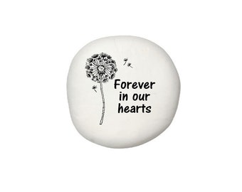 May include: White stone with a black dandelion design and the text "Forever in our hearts".