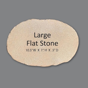 May include: A large, oval-shaped, light beige flat stone with a textured, granular surface. The text "Large Flat Stone" is printed in black in the center, followed by the dimensions "10.5" W X 7" H X .5" D" printed in black below it.