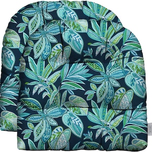 May include: Two outdoor chair cushions with a tropical leaf pattern in shades of teal, green, and white on a navy blue background. The cushions have a rounded top and are designed for comfort and style. The cushions are made of a durable, weather-resistant fabric.