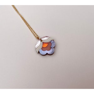 Pode incluir: Um colar de corrente dourada com um pingente de flor em camadas. A flor &eacute; feita de acr&iacute;lico branco, roxo e laranja.