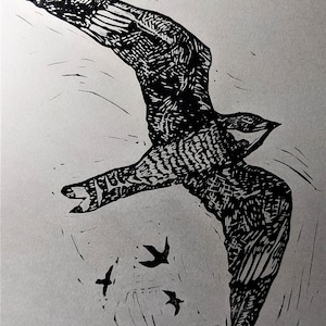 May include: Black and white linocut print of a bird in flight with three smaller birds below it.