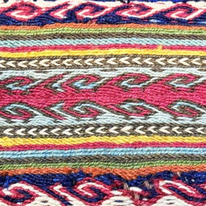 May include: Close-up of a woven textile with a vibrant, multicolored design. The pattern features horizontal bands of various colors, including blue, green, yellow, and red, with intricate geometric and wave-like motifs. The texture appears to be coarse and handmade.