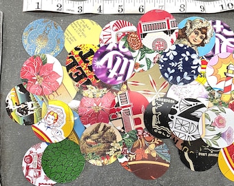 May include: A collection of colorful, circular vintage bottle caps with various designs, including floral patterns, portraits, and text. A silver knife and a measuring tape are also present.